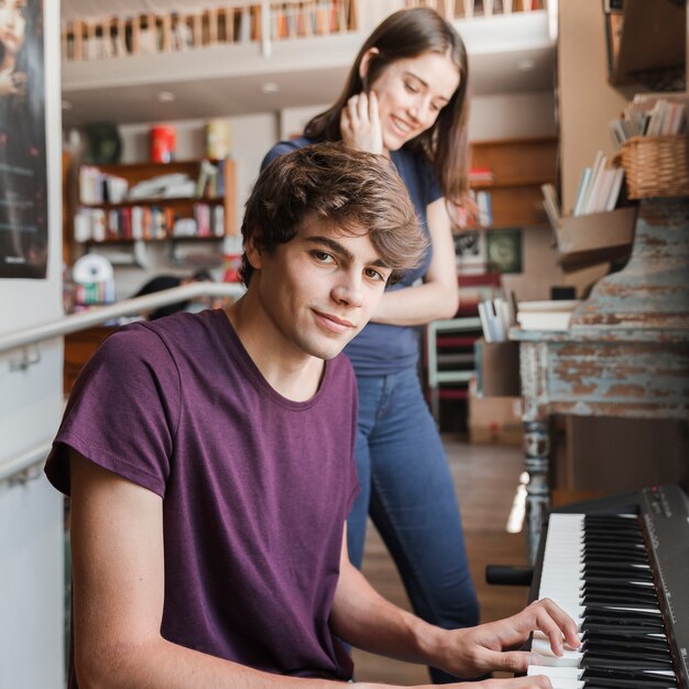 Teen boy playing piano for girlfriend in cozy room