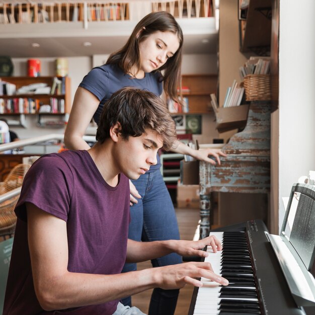 Teen boy playing piano for girlfriend