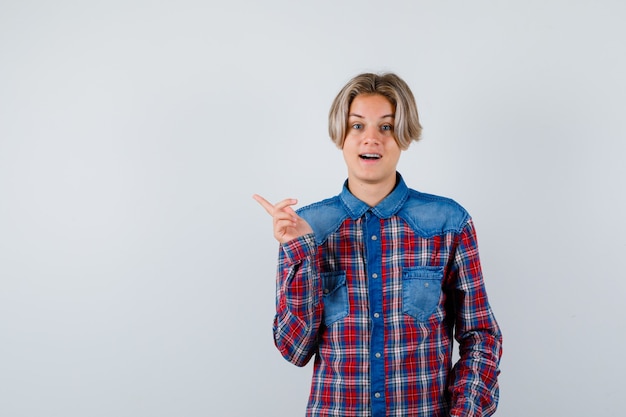 Teen boy pointing at upper left corner in checkered shirt