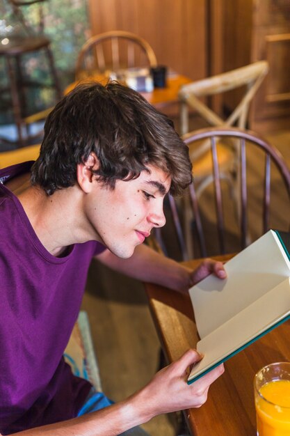 teen boy reading book in cafe
