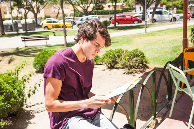 Teen boy reading book in park