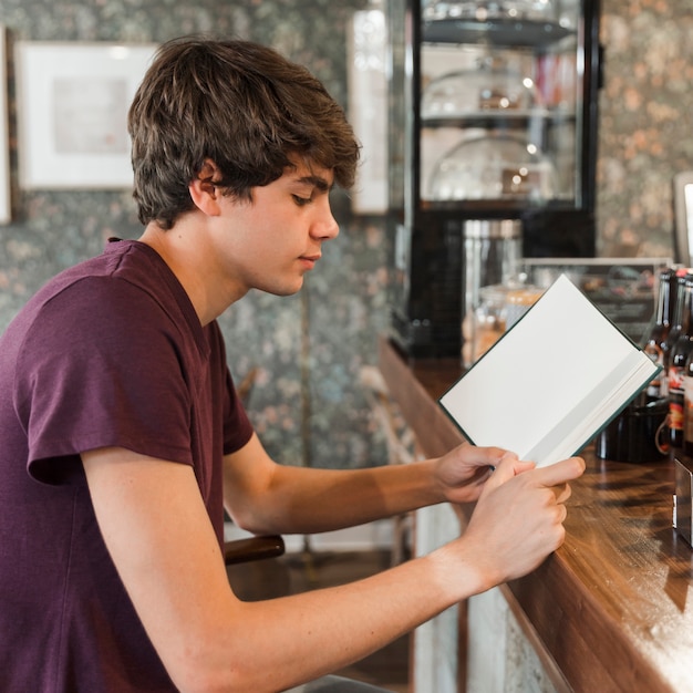 Teen boy reading at cafe counter