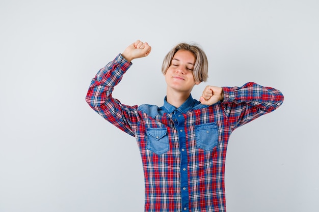 Teen boy stretching upper body in checkered shirt and looking relaxed. front view.