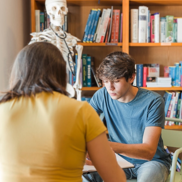 Foto gratuita ragazzo teenager che studia con la fidanzata in biblioteca