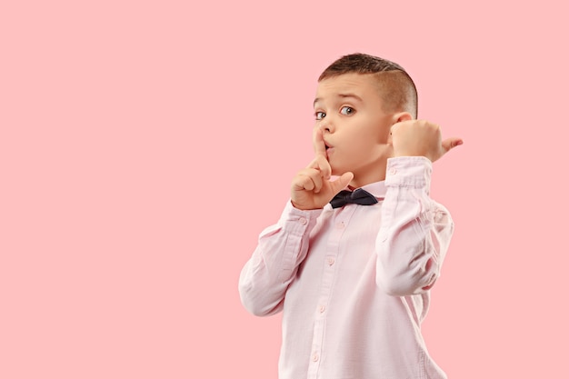 Free photo the teen boy whispering a secret behind her hand over pink background