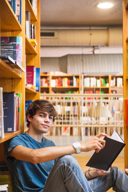 Foto gratuita ragazzo teenager con il libro che guarda l'obbiettivo