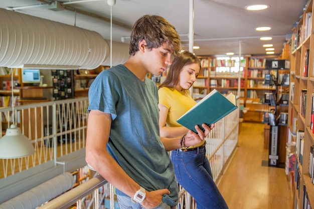 Free photo teen couple leaning on railing and reading