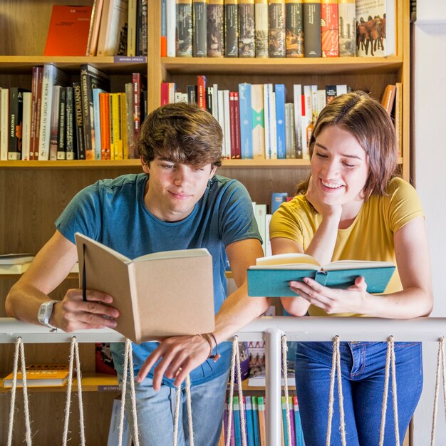 Teen couple reading near railing