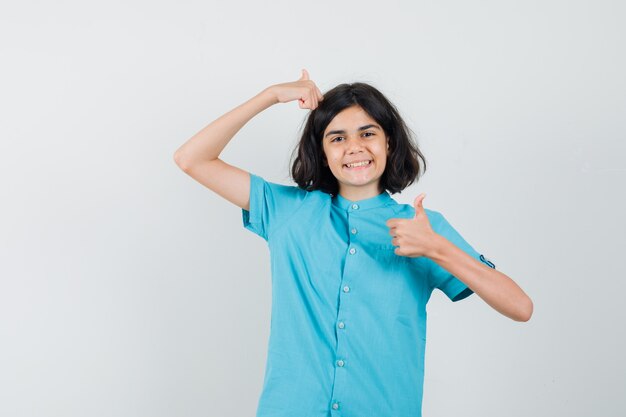 Teen girl in blue shirt showing thumb up and looking merry