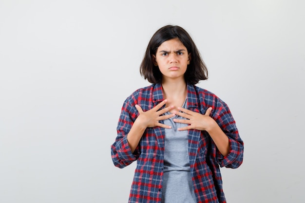 Free photo teen girl in casual clothes holding hands on chest and looking gloomy , front view.