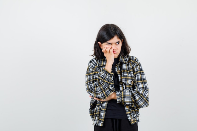 Free photo teen girl in casual shirt pressing hand on cheek, looking away and looking bored , front view.