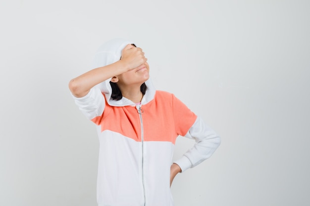 Teen girl covering eyes with hand in sweatshirt and looking patient