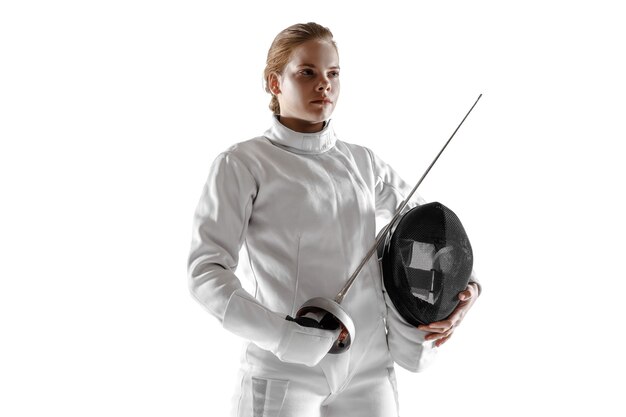 Teen girl in fencing costume with sword in hand isolated on white studio background.