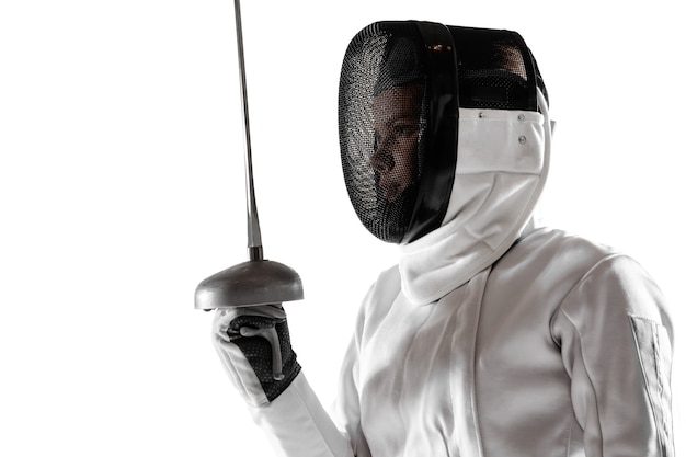 Teen girl in fencing costume with sword in hand isolated on white studio background.