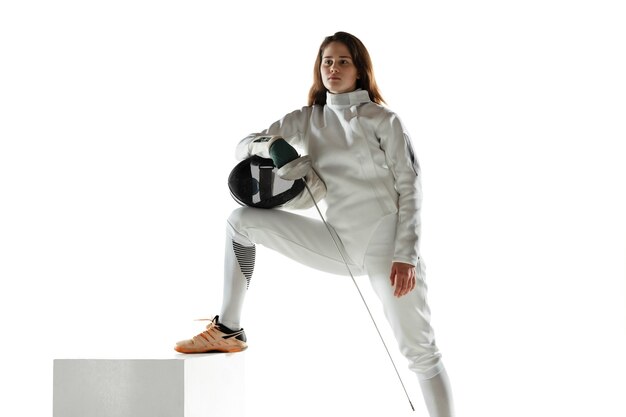 Teen girl in fencing costume with sword in hand isolated on white wall