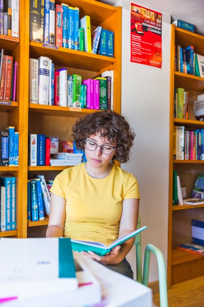 Teen girl in glasses reading at table