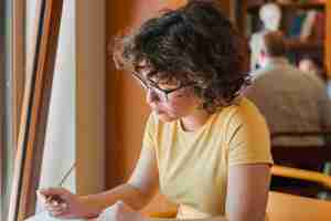 Free photo teen girl in glasses studying near window