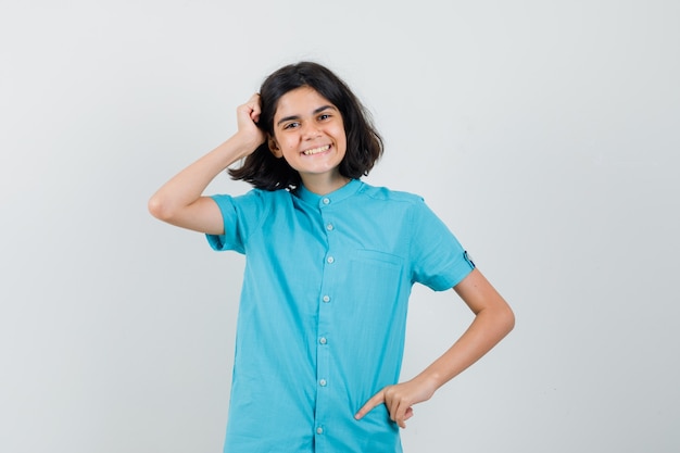 Teen girl holding hand on hair while smiling in blue shirt and looking cute