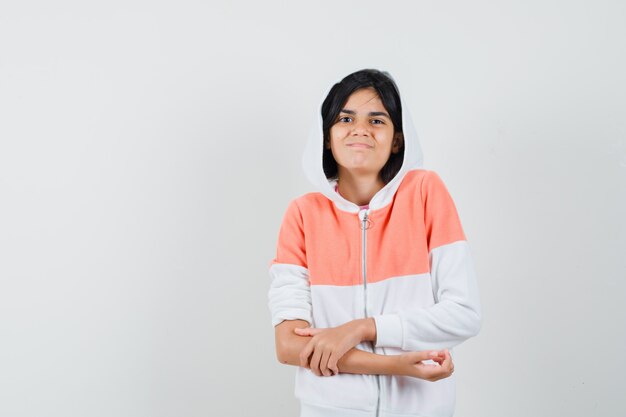 Teen girl holding hand on her arm in jacket and looking uncomfortable.