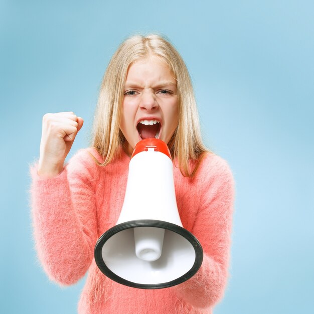 Teen girl making announcement with megaphone at blue studio