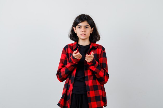 Teen girl pointing in casual shirt and looking pensive , front view.