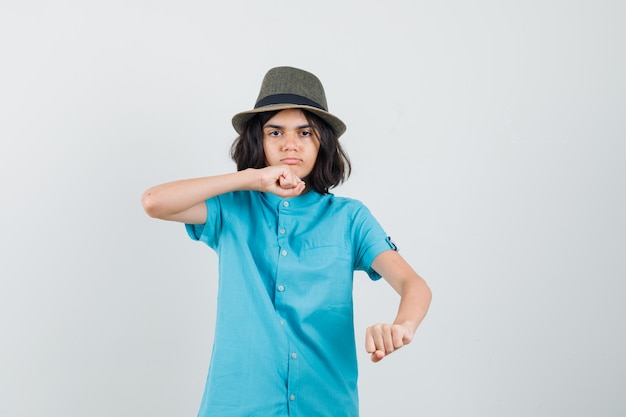 Teen girl raising her fists for fighting in blue shirt and looking serious