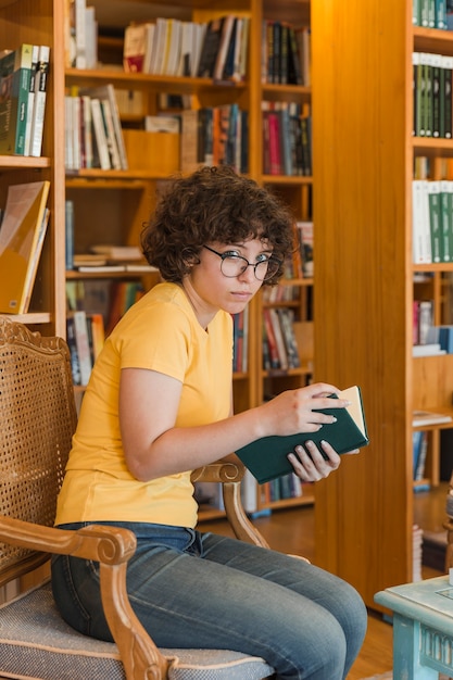 Ragazza teenager che legge nella biblioteca piacevole