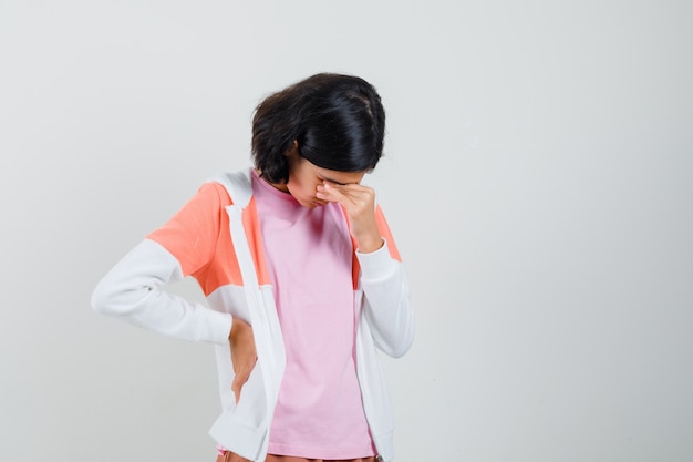 Teen girl rubbing her eyes in jacket,pink shirt and looking stressful.
