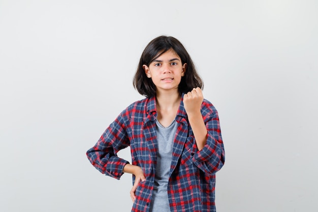 Teen girl showing winner gesture in casual clothes and looking lucky , front view.