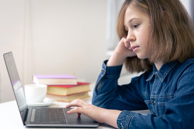 La ragazza adolescente si siede di fronte a un computer portatile per l'apprendimento online