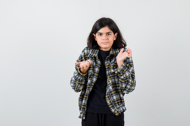 Free photo teen girl spreading palms in clueless gesture in casual shirt and looking pensive , front view.