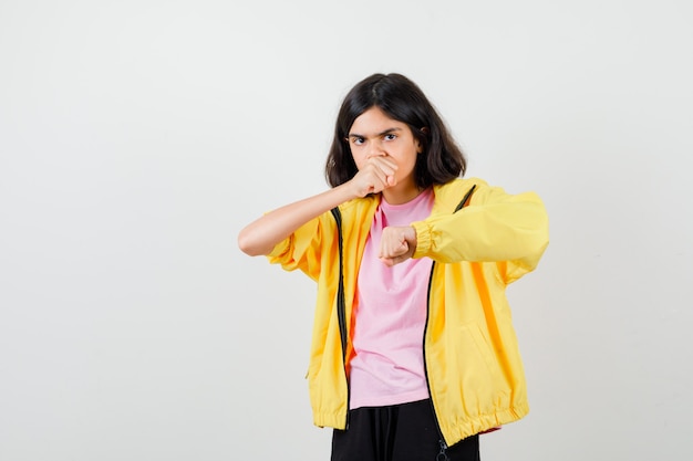 Девушка-подросток, стоящая в позе боя в футболке, куртке и смотрящая сосредоточенно, вид спереди.