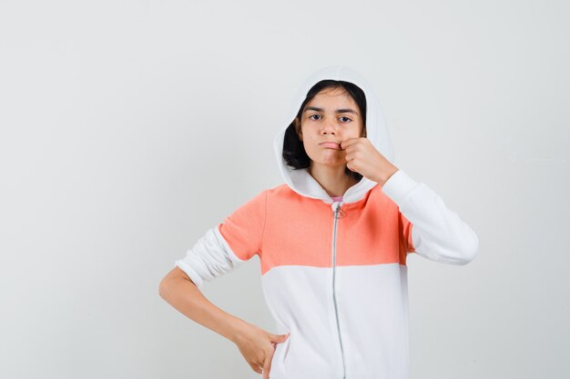 Teen girl in sweatshirt showing zip gesture.