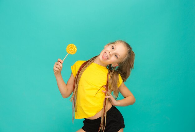The teen girl with colorful lollipop on a blue wall