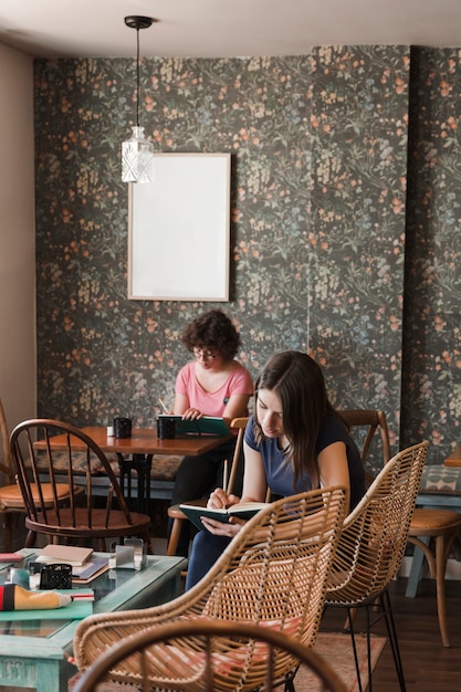 Teen girls writing in notebooks in cafe