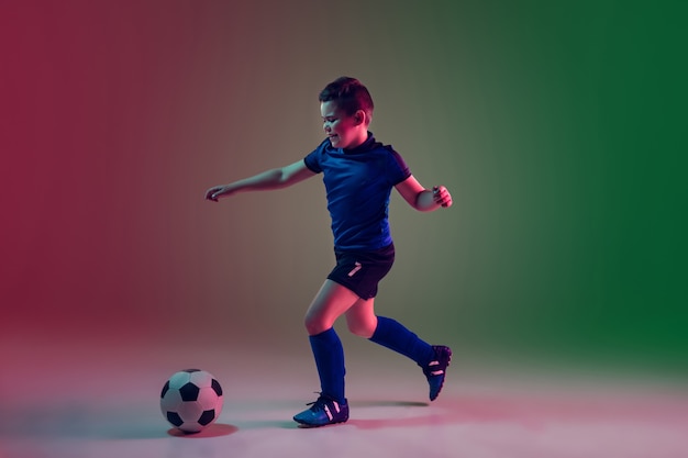 Teen male football or soccer player, boy on gradient in neon light