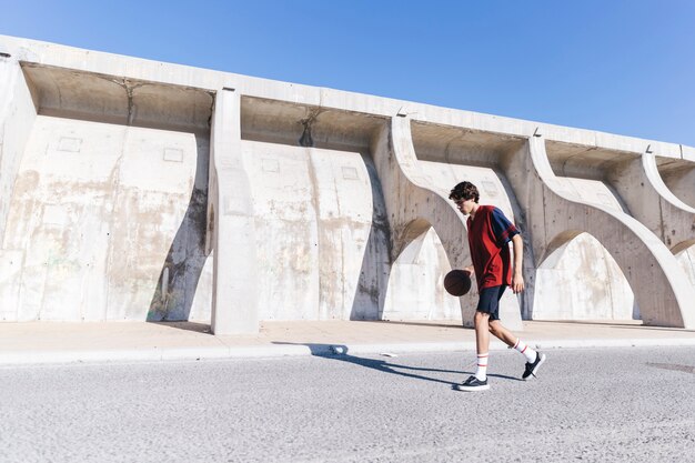 Teen practicing basketball near surrounding wall