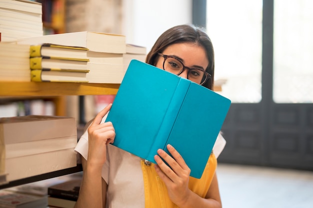 Teen schoolgirl hiding face behind book