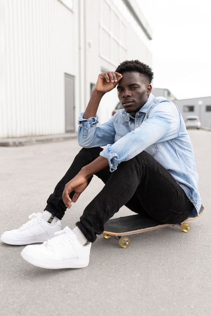 Teen sitting on skateboard full shot