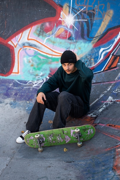 Foto gratuita adolescente che si siede nel colpo pieno dello skatepark