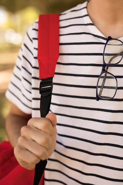 Teen student with glasses carrying backpack