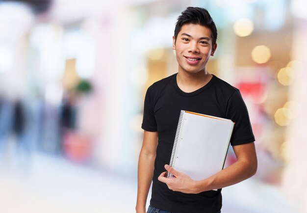 Teen with a big smile holding his blank notebook