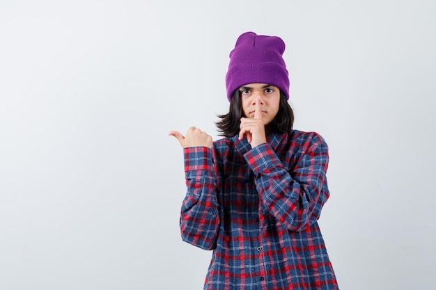 Teen woman in checkered shirt and beanie gesticulating isolated