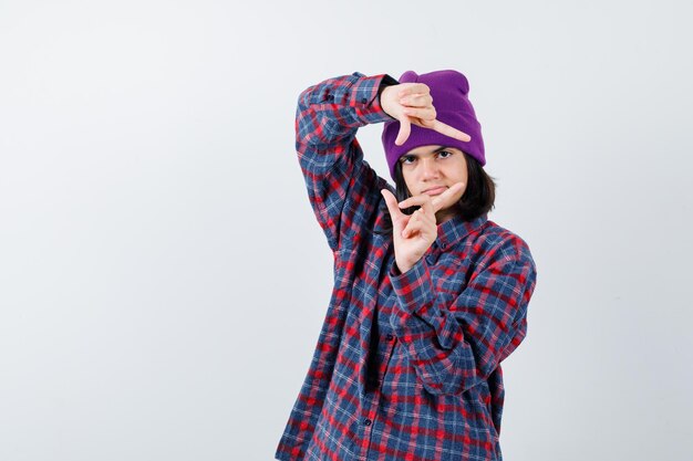 Teen woman in checkered shirt and beanie gesticulating isolated