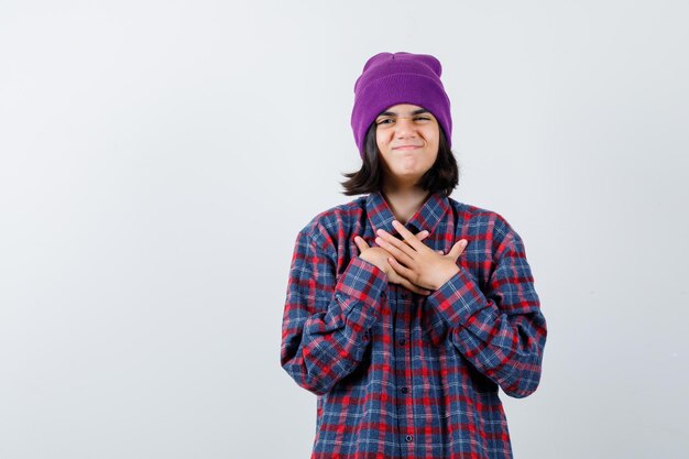 Teen woman in checkered shirt and beanie gesticulating isolated