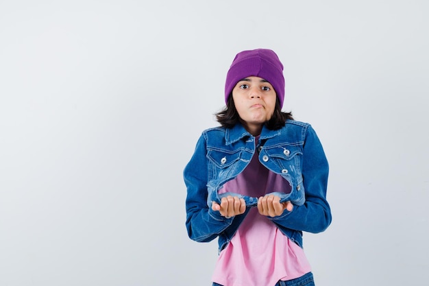 Teen woman in checkered shirt and beanie gesticulating isolated