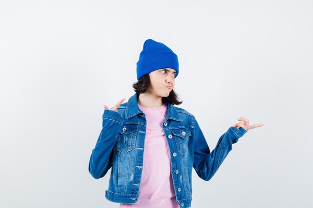 Teen woman in checkered shirt and beanie gesticulating isolated