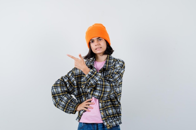 Teen woman in checkered shirt and beanie gesticulating isolated