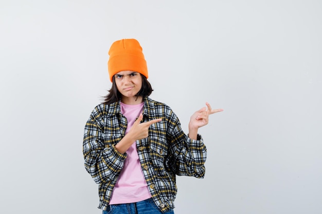 Teen woman in checkered shirt and beanie gesticulating isolated