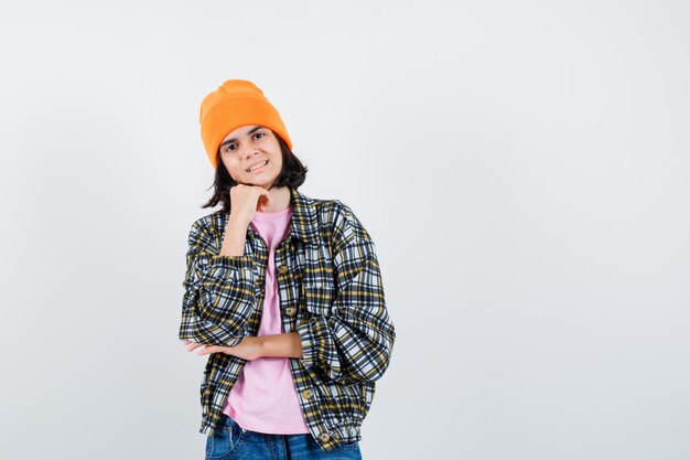 Teen woman in checkered shirt and beanie gesticulating isolated